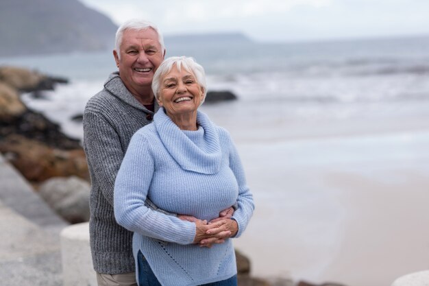 Senior paar omhelzen elkaar op het strand