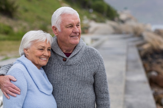 Senior paar omhelzen elkaar op het strand