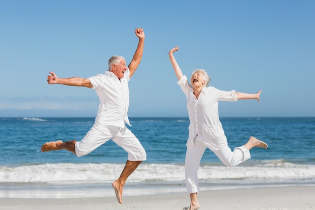 Senior paar springen op het strand