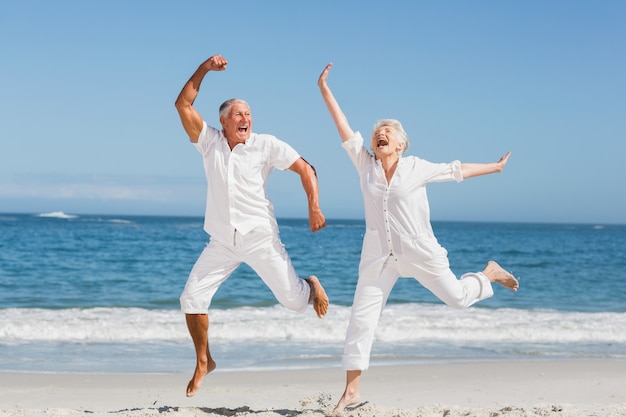 Senior paar springen op het strand