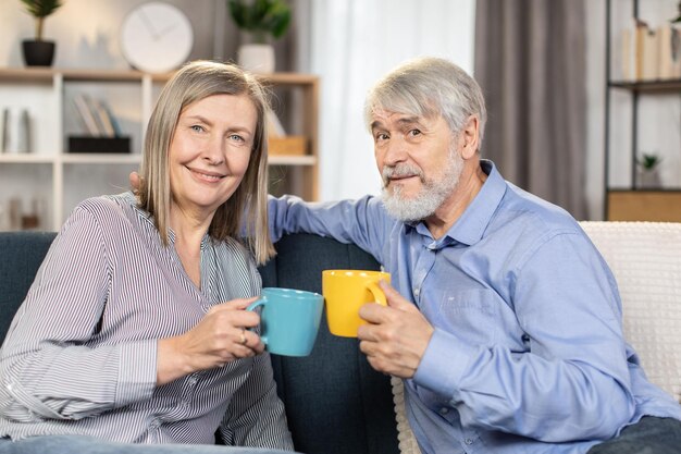 Senior paar thee drinken op de bank in gezellige woonkamer