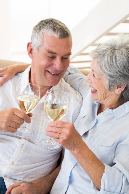 Senior paar zittend op de bank met witte wijn