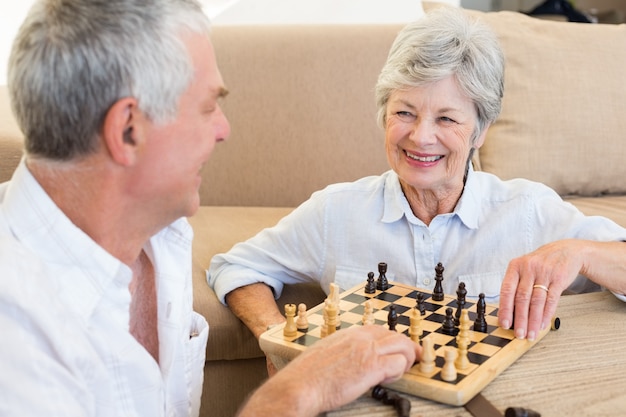 Senior paar zittend op de vloer Schaken