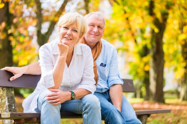 Senior paar zittend op een deel bankje in de herfst