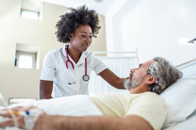 Senior patient on bed talking to female doctor in hospital room