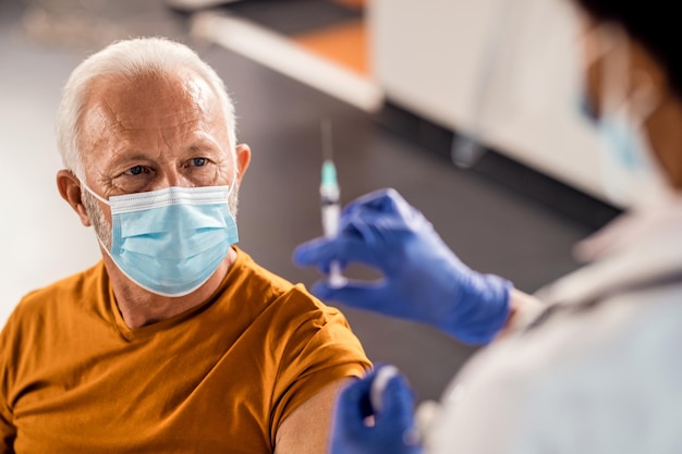 Senior patient getting vaccinated at medical clinic during coronavirus pandemic