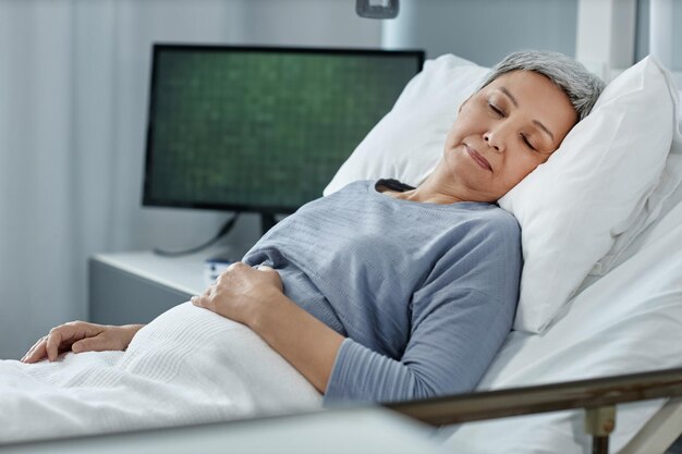 Photo senior patient lying on bed in ward