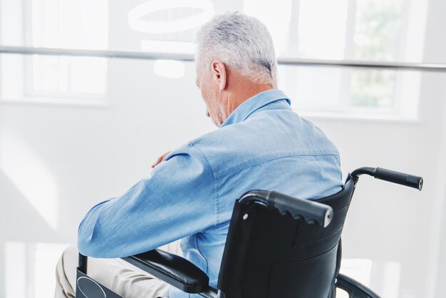 Senior patient sitting in wheelchair suffering from painful illnesses in hospital