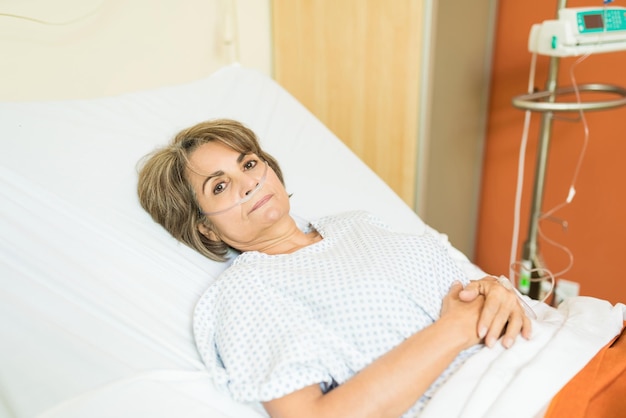 Senior patient suffering from disease lying on hospital bed and making eye contact