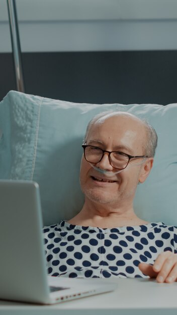 Старший пациент разговаривает по видеозвонку в больничной палате