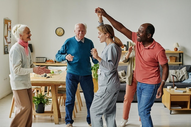 Senior people dancing with their caregiver during dance lesson in nursing home