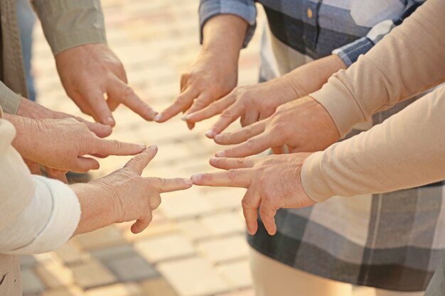 Foto anziani della casa di cura che uniscono le mani come simbolo di unità all'aperto