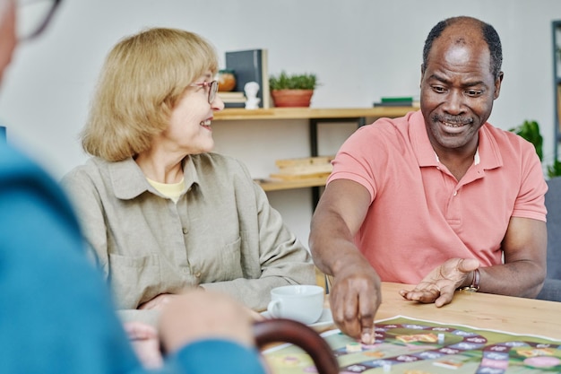 Senior people having fun playing board game at table in the room