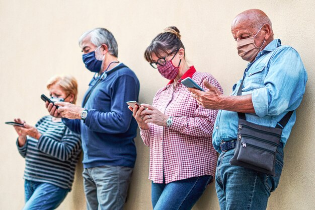 Senior people using smartphones with face mask on