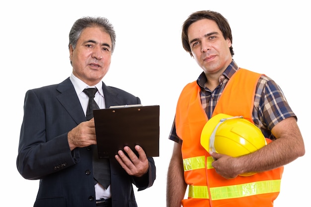 senior Persian businessman holding clipboard with young construction worker man