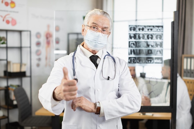 Senior physician in face mask posing with crossed arms