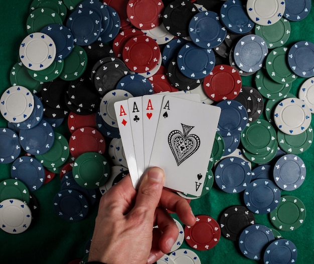 Poker senior. il giocatore ha in mano quattro carte da gioco, quattro assi. sfondo di fiches del casinò