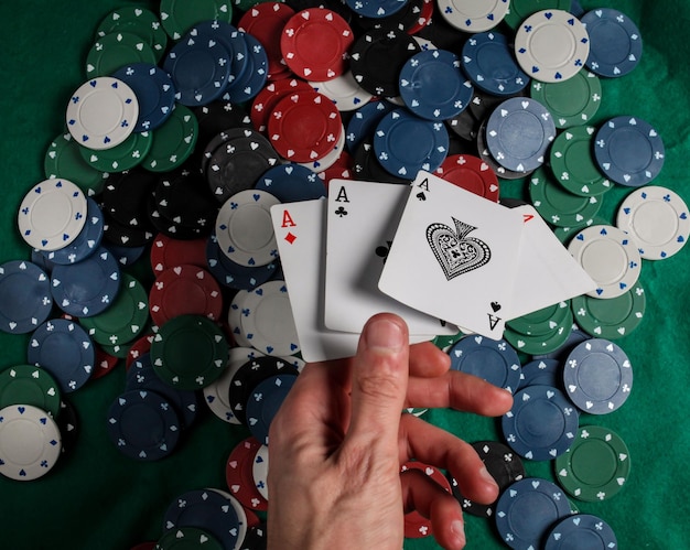 Poker senior. il giocatore ha in mano quattro carte da gioco, quattro assi. sfondo di fiches del casinò