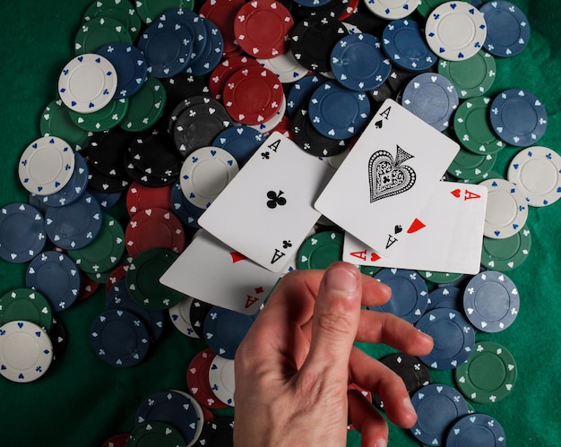 Poker senior. il giocatore ha in mano quattro carte da gioco, quattro assi. sfondo di fiches del casinò