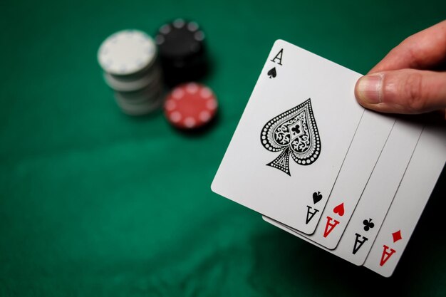 Photo senior poker. the player holds in his hand four playing cards, four aces. casino tabke background