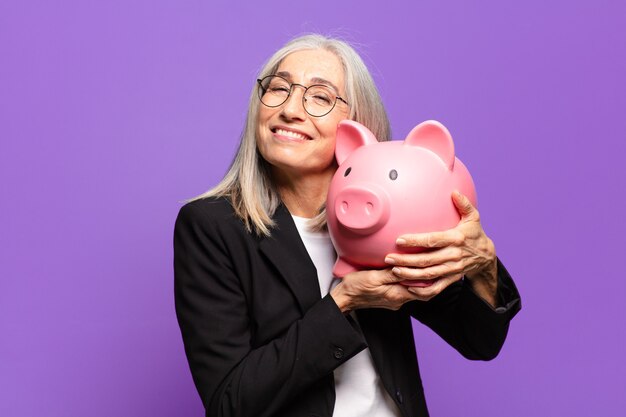 Senior pretty businesswoman with a piggy bank