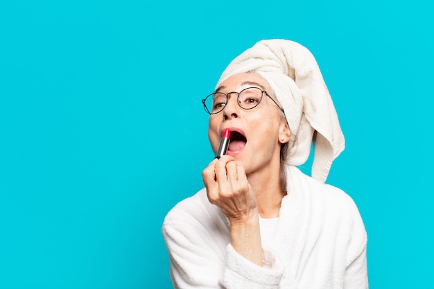 Senior pretty woman after shower making up and wearing bathrobe