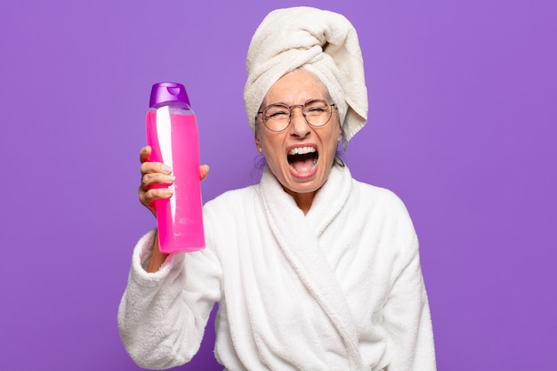 Senior bella donna dopo la doccia indossando accappatoio. concetto di prodotti per la pulizia del viso o doccia