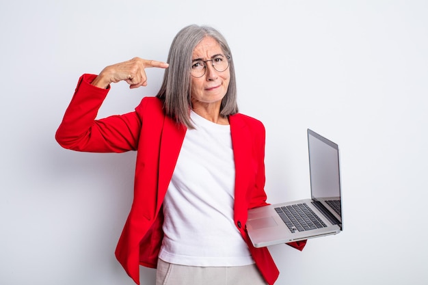 Una bella donna anziana che si sente confusa e perplessa, mostrando che sei pazzo. concetto di business e laptop