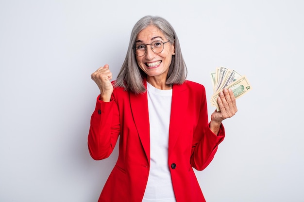 Senior pretty woman feeling shocked,laughing and celebrating success. business and banknotes concept