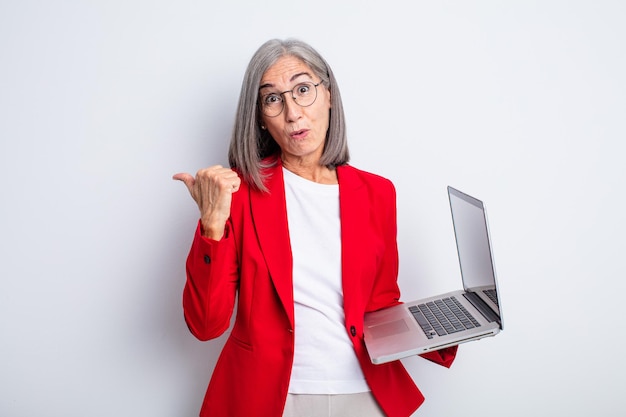 Senior pretty woman looking astonished in disbelief. business and laptop concept