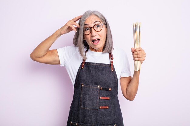 幸せそうに見える年配のきれいな女性は、ブラシで驚いて驚いた芸術家です