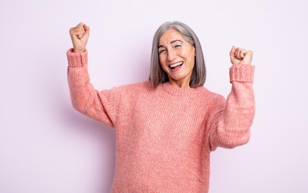 意気揚々と叫び、興奮し、幸せで驚きの勝者のように見え、祝う年配のきれいな女性