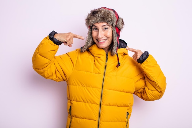 Senior pretty woman smiling confidently pointing to own broad smile. winter concept