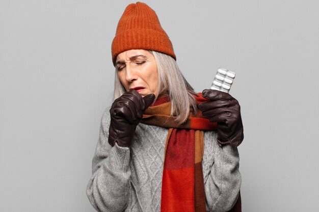 Senior pretty woman with a pills tablet wearing winter clothes. flu concept