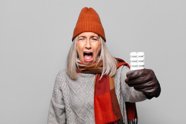 Senior pretty woman with a pills tablet wearing winter clothes