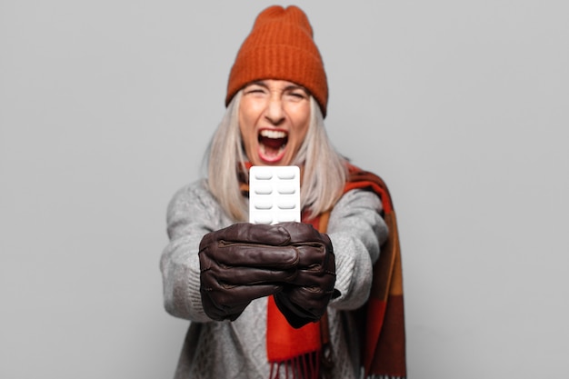 Photo senior pretty woman with a pills tablet wearing winter clothes.