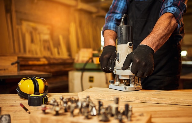 Senior Professional carpenter in uniform working of manual milling machine in the carpentry workshop