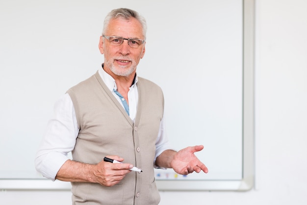 Senior professor explaining while standing near marker board