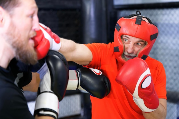 Senior retired healthy athletic old man is fighting training boxing in gloves sparring Box fight