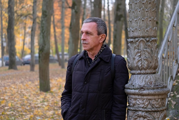 Senior retired man on beautiful autumn day in park stands and rests