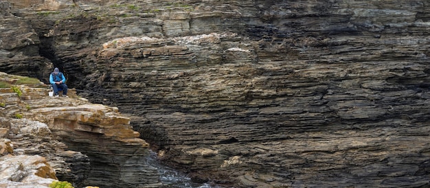 Premium Photo  Senior and retired man in blue fisherman's cap and vest  preparing his fishing rod and hooks sitting on the edge of a rocky cliff  with moss and lime of