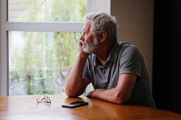 Photo senior retired man sitting at home alone while quarantine