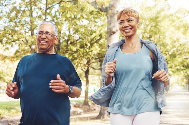 Foto senior runner coppia parco e fitness con sorriso lavoro di squadra o motivazione per il benessere sotto il sole estivo felice uomo anziano donna e squadra di corsa sugli alberi per la salute fisica o allenamento all'aperto