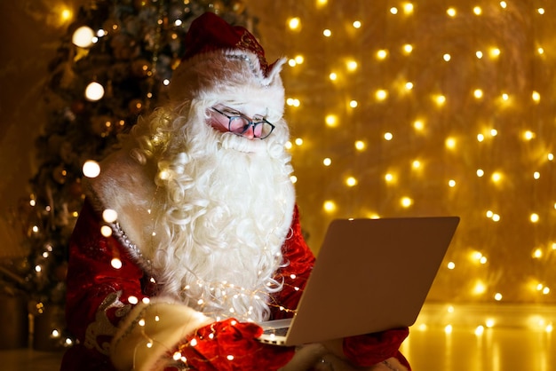 Senior santa in rode klederdracht online chatten op laptop tijdens videogesprek over kerstmis...