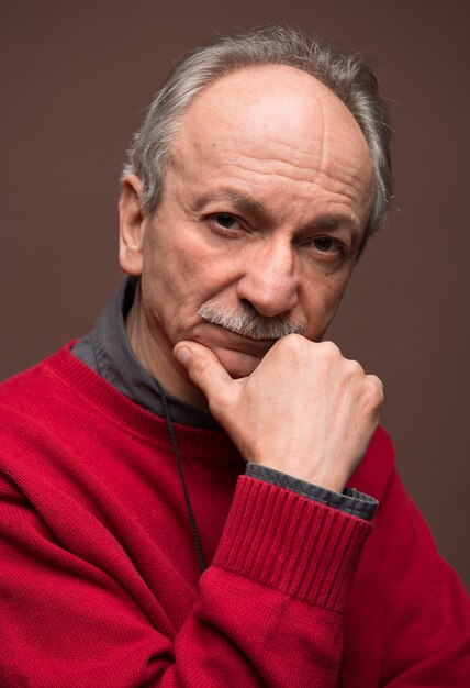 Senior serious man  posing in studio over brown background