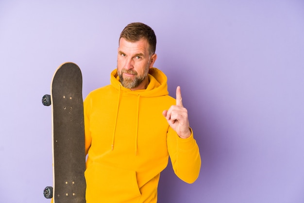 Senior skater man geïsoleerd op paarse achtergrond met nummer één met vinger.