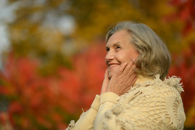 Senior smiling woman in park praying