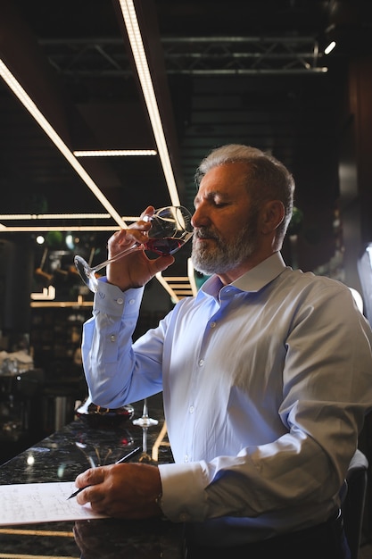 A senior sommelier is tasting red wine.