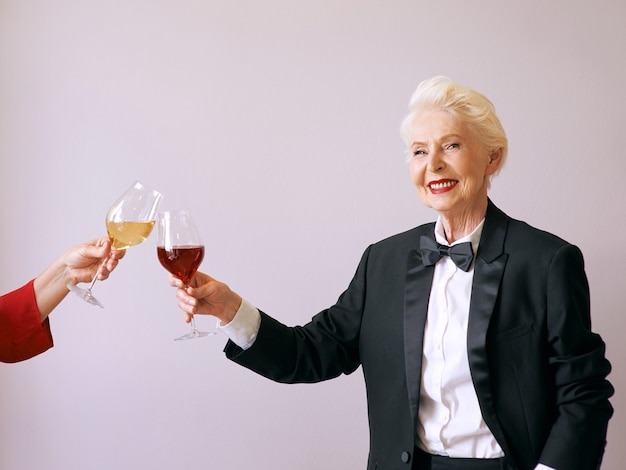 senior sommelier woman in tuxedo with glass or red wine at the party