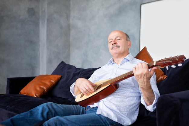 Senior Spaanse man thuis die gitaar leert spelen